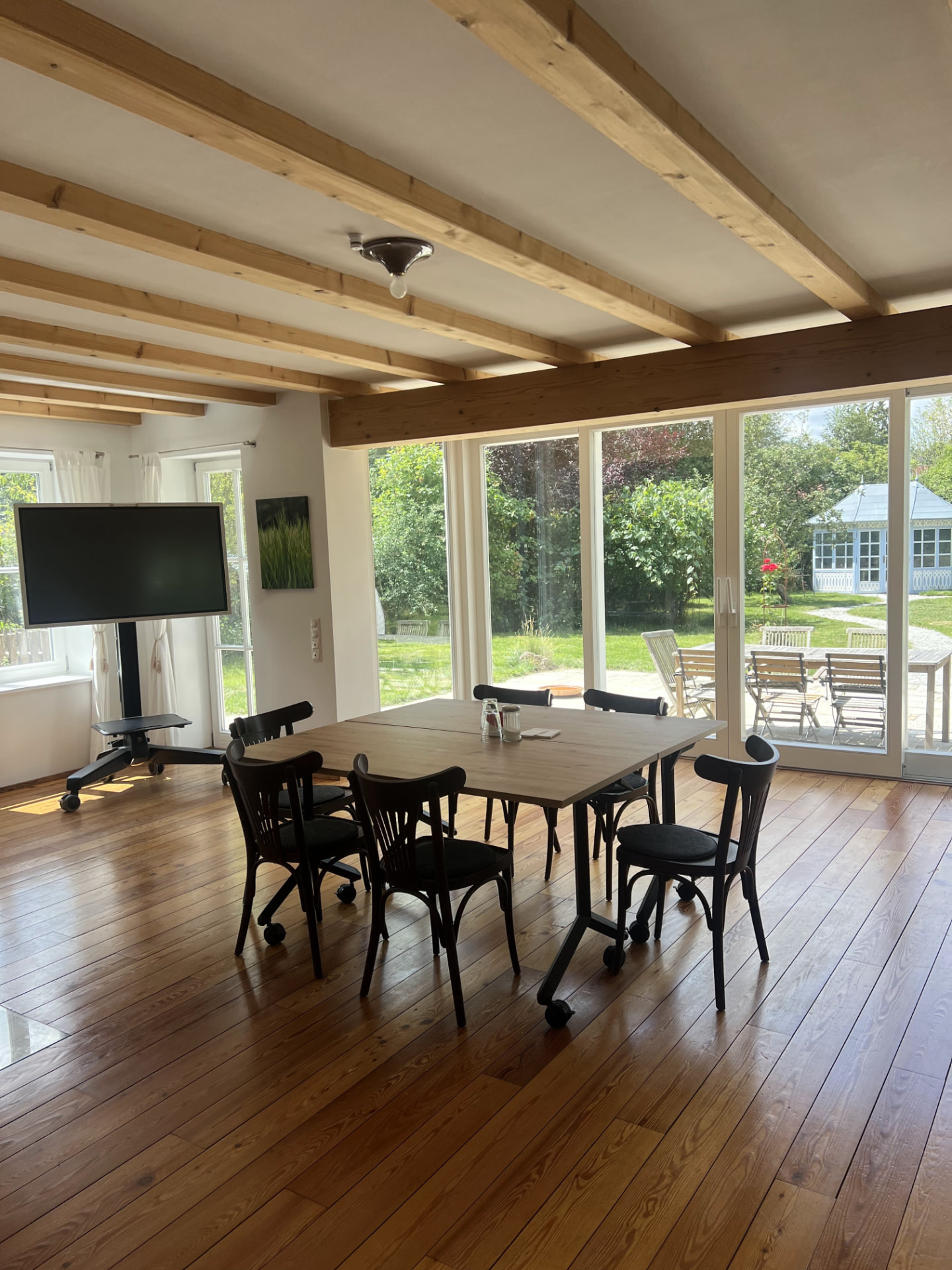 Seminarraum im Haus am Moosbach mit Bildschirm und Blick in den Garten